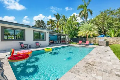 a swimming pool with a pool noodle in front of a house at The Palms -Mini Golf , Foosball Table, Heated Pool ,Baby items ,BBQ in Miami