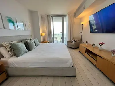 a bedroom with a large bed and a television at Sunset Views & Style, Chic Beachfront in Miami -A in Hallandale Beach