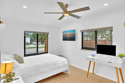a bedroom with a bed with a desk and a ceiling fan at Tropical Oasis With heated pool 10 mins airport & 5 mins Beach in Hollywood
