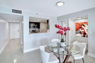 a dining room with a glass table and white chairs at Stay in Love! Miami Skyline Views, Renovated in Miami