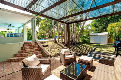 a patio with wicker chairs and a glass table at Miami Dream Home/ Pool/Jacuzzi/ Fire Pit in Miami