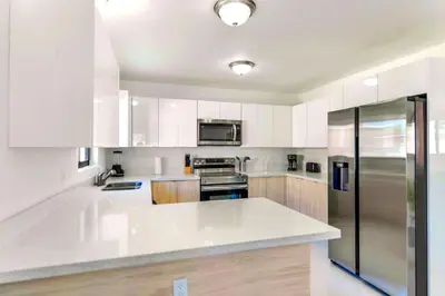 a kitchen with white cabinets and a stainless steel refrigerator at Stunning 3-Bedroom Duplex with Free Parking in Miami