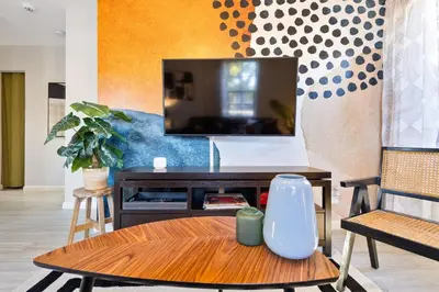 a living room with a table and a tv at Casa Limon - Private Heated Pool Prime Location & Parking in Fort Lauderdale