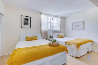 two beds in a white room with yellow blankets at Paradise Retreat, Near Beach, Casino, and More in Hollywood