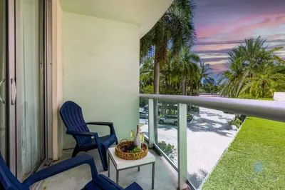 a balcony with two chairs and a table and palm trees at Paradise Retreat, Near Beach, Casino, and More in Hollywood