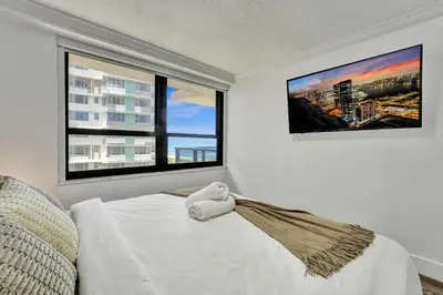 a bedroom with a white bed and two windows at Breathtaking resort condo w beach service Unit 908 in Miami Beach
