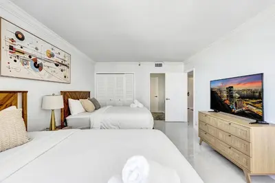 a white bedroom with two beds and a flat screen tv at Breathtaking resort condo w beach service Unit 908 in Miami Beach