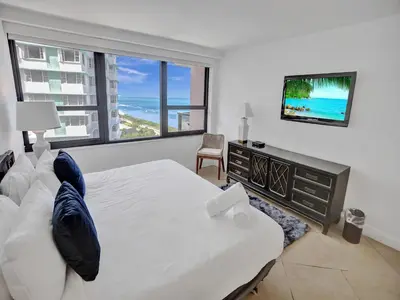 a bedroom with a large bed and a television at Modern Ocean View Condo Beach Service Unit 1206 in Miami Beach