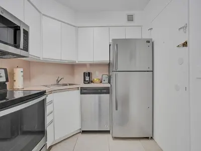 a kitchen with white cabinets and a refrigerator at Cozy 2 Bedroom Ocean View Beach Service 707 in Miami Beach