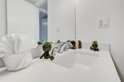 a white bathroom with a sink and a mirror at Ocean View condo w beach service 411 in Miami Beach