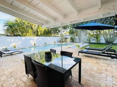 a patio with a table and chairs and a pool at Tropical Oasis House Private Pool Family Yard in Fort Lauderdale