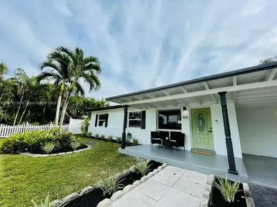 a white house with a porch and palm trees at Tropical Oasis House Private Pool Family Yard in Fort Lauderdale