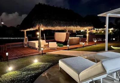 a backyard with a deck with chairs and a pavilion at night at Ocean House in Dania Beach