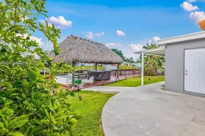 a house with a thatched roof and a yard at Ocean House in Dania Beach