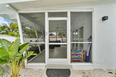 a white house with a large sliding glass door at Seashell Walk To The Beach Comfy Beds Firepit Pool in Fort Lauderdale