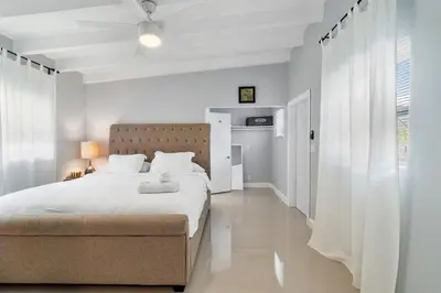 a white bedroom with a large bed and a window at Seashell Walk To The Beach Comfy Beds Firepit Pool in Fort Lauderdale