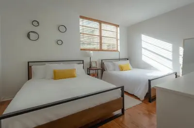 two beds in a room with white walls and windows at Tides Condominiums in Hollywood