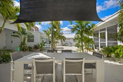 a white dining table and chairs in a yard at Coconut Walk To The BeachComfy Beds Firepit Pool in Fort Lauderdale