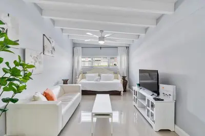 a white living room with a bed and a couch at Coconut Walk To The BeachComfy Beds Firepit Pool in Fort Lauderdale