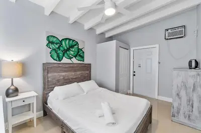 a bedroom with a bed with a plant on the wall at The Sandbar Walk To Beach Comfy Beds Firepit Pool in Fort Lauderdale
