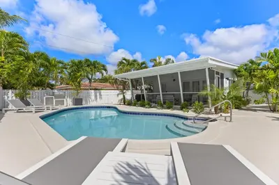 a swimming pool in front of a house at The Sandbar Walk To Beach Comfy Beds Firepit Pool in Fort Lauderdale