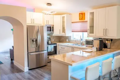 a kitchen with white cabinets and a stainless steel refrigerator at 5 min to airport and 15 min to beach! in Fort Lauderdale
