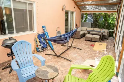 a patio with chairs and a hammock and a couch at 5 min to airport and 15 min to beach! in Fort Lauderdale