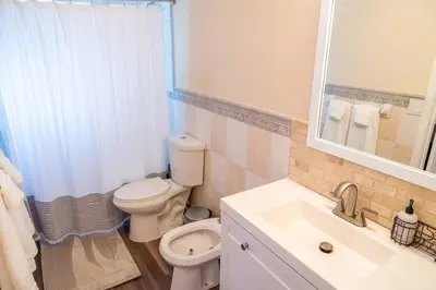 a bathroom with a toilet and a sink and a mirror at 5 min to airport and 15 min to beach! in Fort Lauderdale