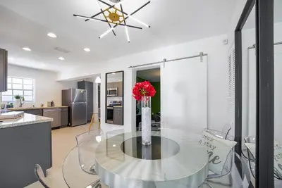a dining room with a glass table with a vase of flowers at Dior Lake Front Villa With Infinity Pool in Miami Gardens