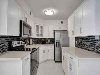a kitchen with white cabinets and stainless steel appliances at Amazing Ocean View Condo Beach Service 1111 in Miami Beach