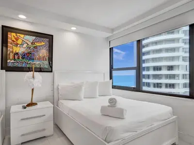 a bedroom with a white bed and a large window at Amazing Ocean View Condo Beach Service 1111 in Miami Beach