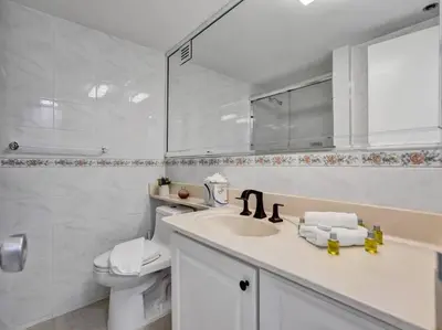 a bathroom with a sink and a toilet and a mirror at High Floor Beachfront Condo Beach Service 1509 in Miami Beach