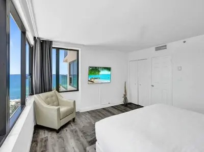 a white bedroom with a large bed and a chair at Full ocean view Huge private terrace 1002 in Miami Beach