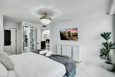 a white bedroom with a large bed and a chandelier at Cozy Ocean View Condo Beach Service and Pool 808 in Miami Beach