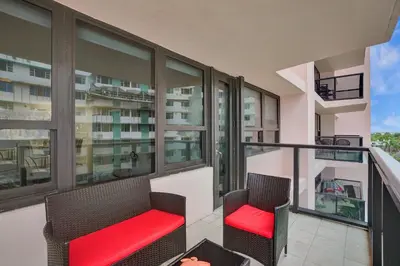 an apartment balcony with two chairs and red cushions at Cozy Ocean View Condo Beach Service and Pool 808 in Miami Beach