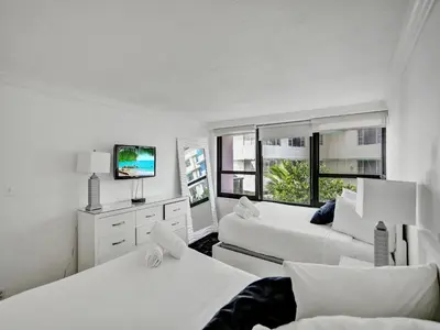 a white room with two beds and a tv at Charming Ocean View Condo Beach Service 516 in Miami Beach