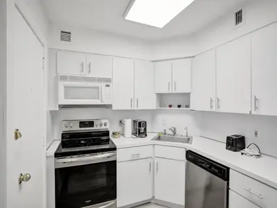 a kitchen with white cabinets and a stove and microwave at Charming Ocean View Condo Beach Service 516 in Miami Beach