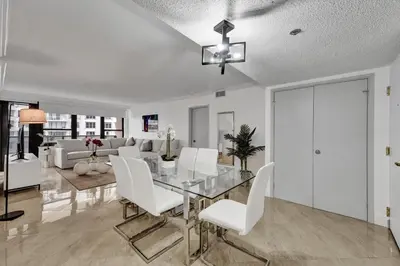 a dining room with a glass table and white chairs at Cozy Ocean View Condo Beach Service 1015 in Miami Beach