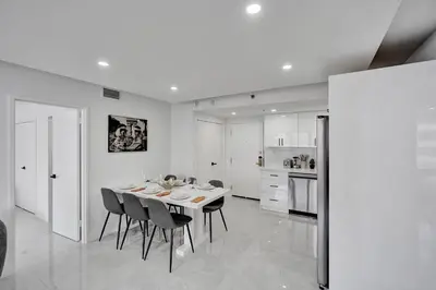a white kitchen with a dining room table and chairs at Relax in Style 3BR 2BA Beach Condo in Oceanfront Resort Pools Gym Sauna 1507 in Miami Beach