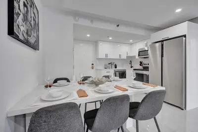 a white kitchen with a table with chairs and a refrigerator at Relax in Style 3BR 2BA Beach Condo in Oceanfront Resort Pools Gym Sauna 1507 in Miami Beach
