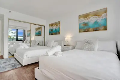 a bedroom with two beds and a mirror at Resort beach condo w beach service 601 in Miami Beach