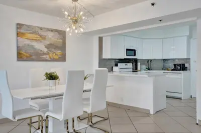 a kitchen with white cabinets and a table and chairs at Resort beach condo w beach service 601 in Miami Beach