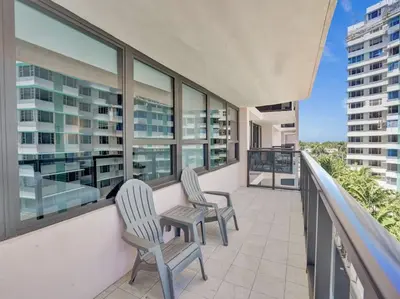 two chairs and a table on a balcony with windows at Lovely Ocean View Condo Beach Service 704 in Miami Beach