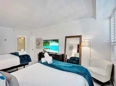 a bedroom with two beds and a chair and a mirror at Luxury Beachfront Condo Beach Service 1418 in Miami Beach