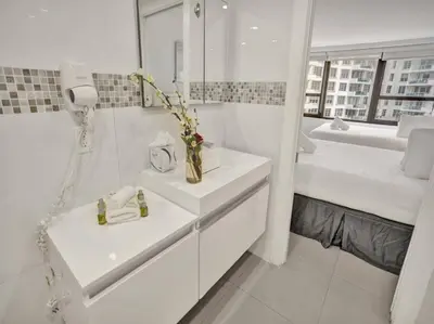 a white bathroom with two sinks and a bed at Spacious Ocean View Condo Beach Service 509 in Miami Beach