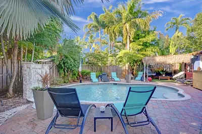 a pool with chairs and a table in a yard at Kiki 1 - Men's Clothing optional Guest Houses in Fort Lauderdale
