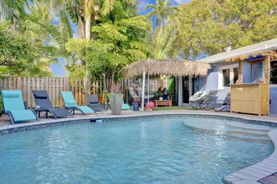 a swimming pool with blue chairs and a house at Kiki 1 - Men's Clothing optional Guest Houses in Fort Lauderdale