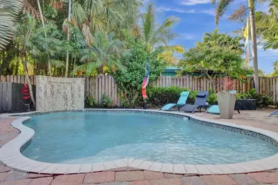 a swimming pool with two chairs and a fence at Kiki 2 - Men's Clothing optional Guest Houses in Fort Lauderdale