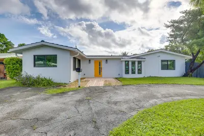 a white house with an orange door at Chic Florida Retreat with Pool, Patio and Gas Grill! in Fort Lauderdale