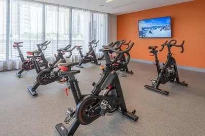 a row of exercise bikes in a gym with orange walls at Stunning Apartment in Downtown Doral in Miami